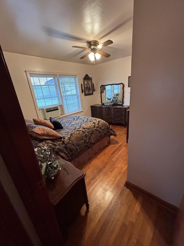 bedroom with light wood-type flooring, ceiling fan, and cooling unit