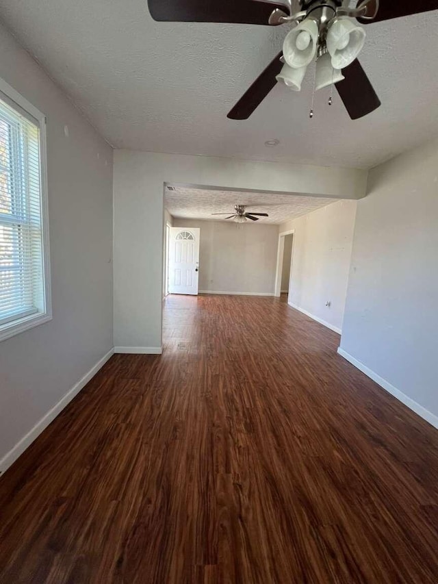 unfurnished living room with a textured ceiling, dark hardwood / wood-style flooring, and ceiling fan