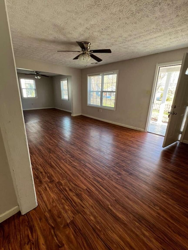 spare room with a textured ceiling, dark hardwood / wood-style floors, and a wealth of natural light