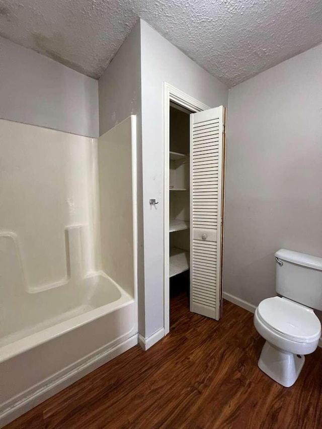 bathroom featuring shower / bath combination, toilet, wood-type flooring, and a textured ceiling