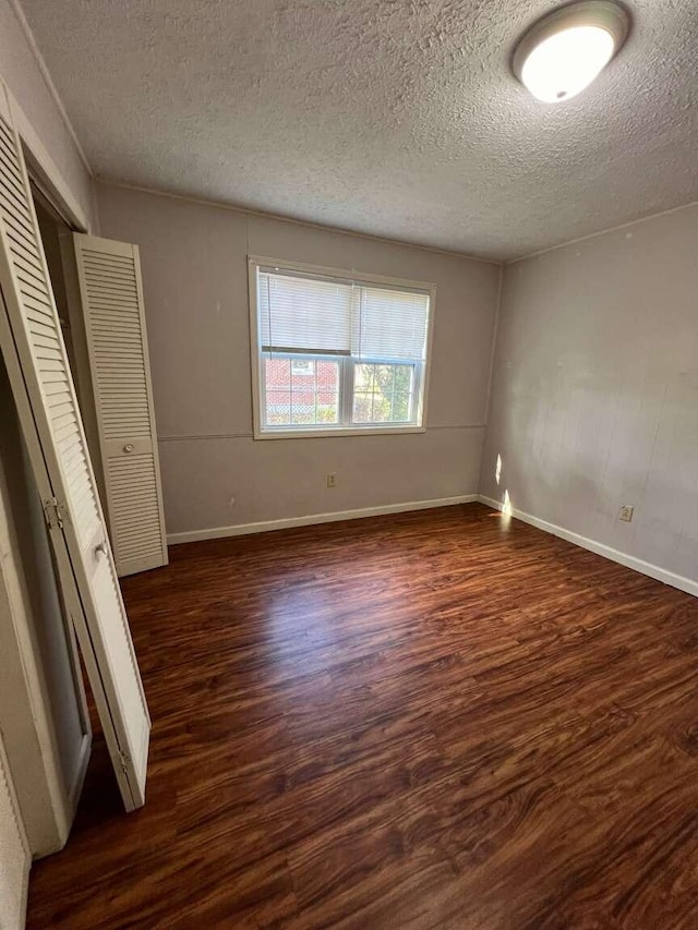 unfurnished bedroom featuring dark hardwood / wood-style flooring and a textured ceiling