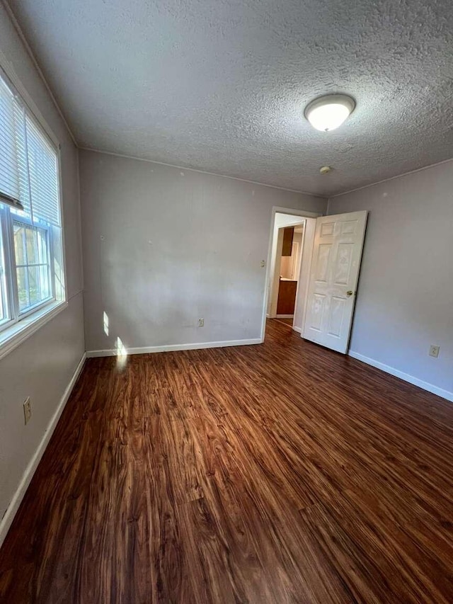 empty room with hardwood / wood-style floors and a textured ceiling