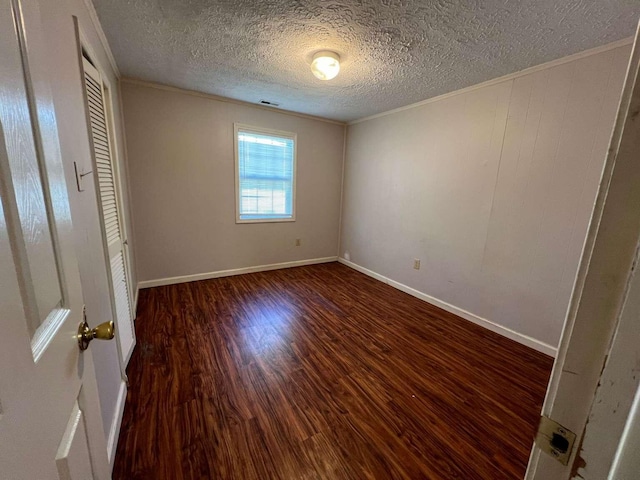 unfurnished bedroom with a textured ceiling, crown molding, and dark wood-type flooring