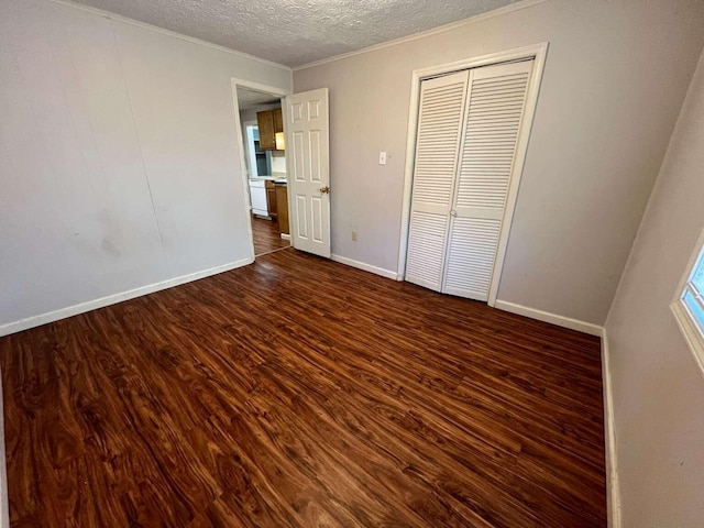 unfurnished bedroom with dark hardwood / wood-style flooring, ornamental molding, a textured ceiling, and a closet