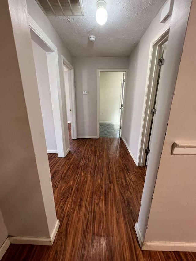 hall with dark wood-type flooring and a textured ceiling