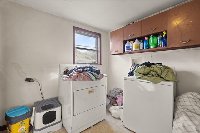 clothes washing area featuring washer and clothes dryer and cabinets