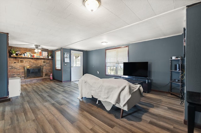 living room with a fireplace, ceiling fan, and dark wood-type flooring