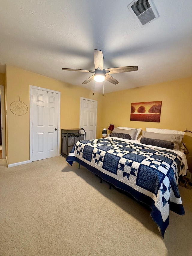 carpeted bedroom featuring ceiling fan and a textured ceiling