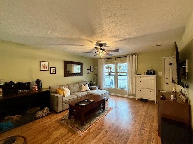 living room featuring hardwood / wood-style flooring, a textured ceiling, and ceiling fan