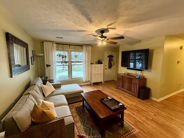 living room featuring hardwood / wood-style floors, a textured ceiling, and ceiling fan