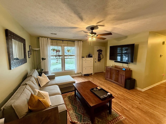 living room featuring ceiling fan, wood-type flooring, and a textured ceiling