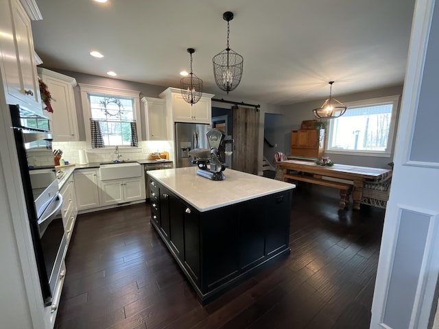 kitchen featuring appliances with stainless steel finishes, sink, a barn door, a kitchen island, and hanging light fixtures