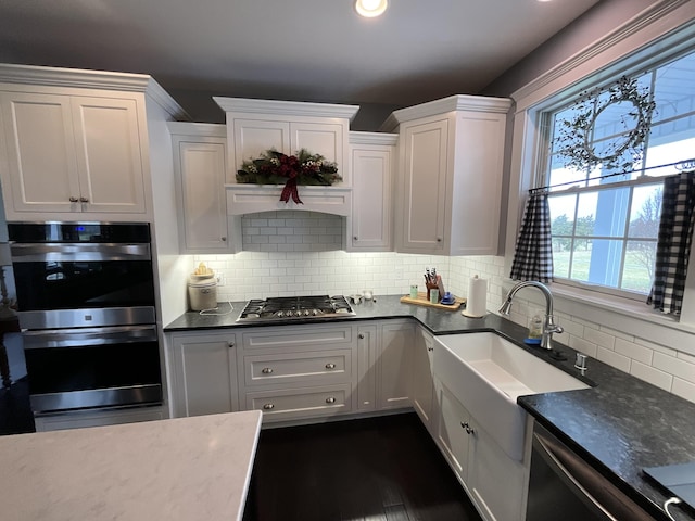 kitchen featuring white cabinets, decorative backsplash, stainless steel appliances, and dark wood-type flooring