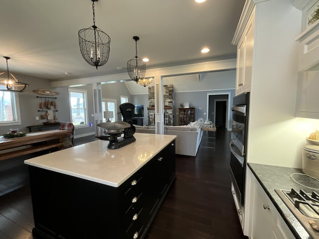 kitchen with decorative light fixtures, a kitchen island, dark hardwood / wood-style flooring, and white cabinetry