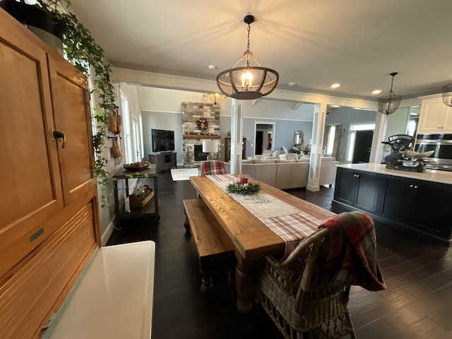 dining area with dark hardwood / wood-style flooring, ornate columns, and a notable chandelier