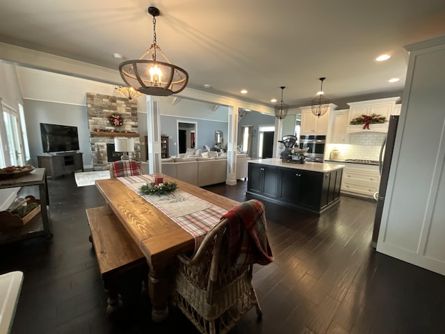 dining area featuring dark hardwood / wood-style floors, an inviting chandelier, a fireplace, and decorative columns