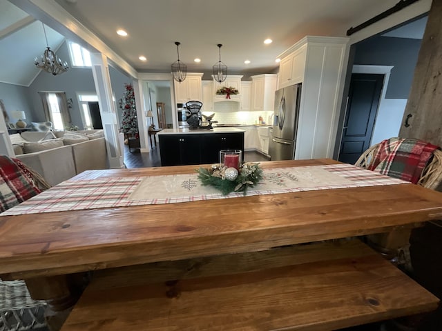 dining space featuring dark wood-type flooring, lofted ceiling, and a notable chandelier