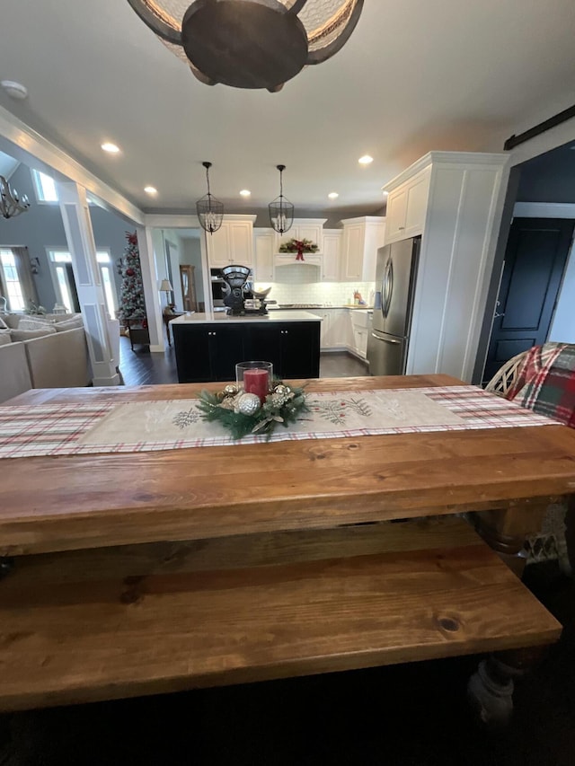 kitchen with hanging light fixtures, a kitchen island, dark hardwood / wood-style floors, stainless steel refrigerator with ice dispenser, and white cabinets