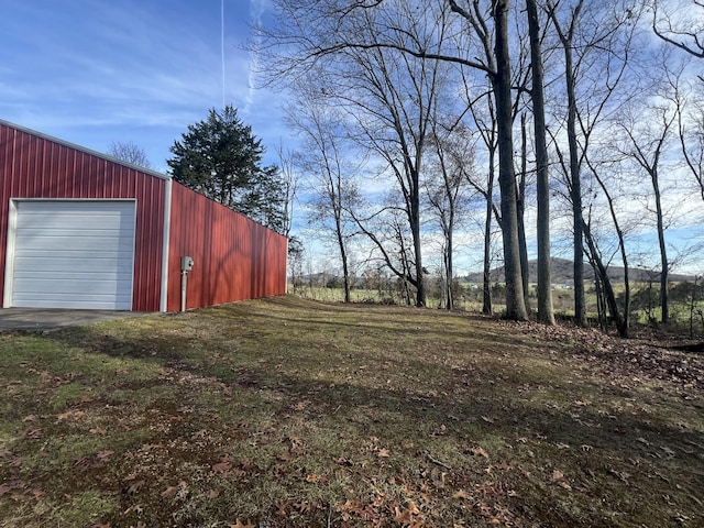 view of yard with a garage and an outbuilding