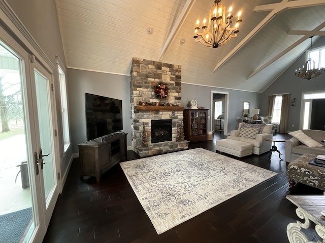 living room with a stone fireplace, dark hardwood / wood-style flooring, a chandelier, and plenty of natural light