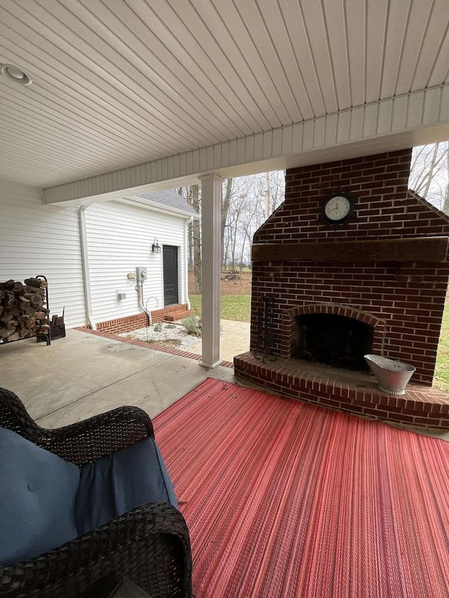 wooden deck featuring an outdoor brick fireplace and a patio area