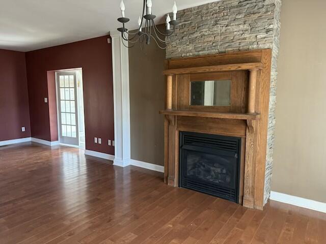 unfurnished living room featuring hardwood / wood-style flooring, a notable chandelier, and a fireplace