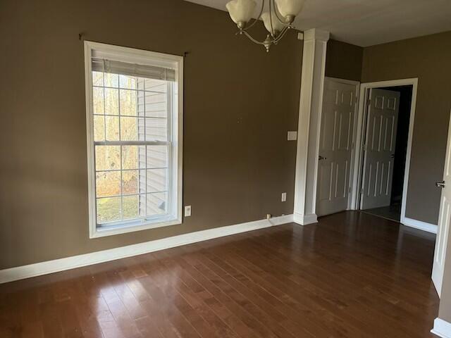 unfurnished room with dark hardwood / wood-style flooring and an inviting chandelier