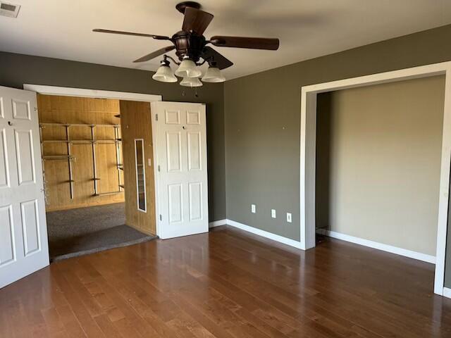 unfurnished bedroom with ceiling fan, a closet, and dark hardwood / wood-style floors