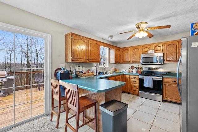 kitchen with a healthy amount of sunlight, ceiling fan, stainless steel appliances, and light tile patterned floors