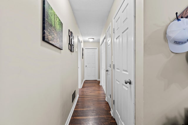 corridor featuring a textured ceiling and dark wood-type flooring