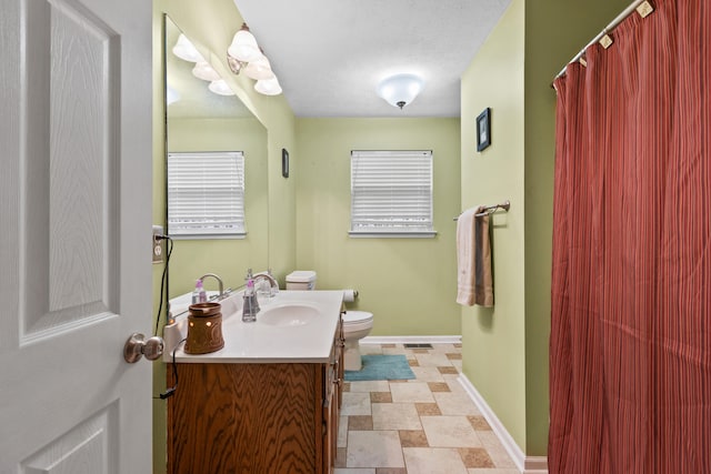 bathroom with vanity, toilet, and a textured ceiling