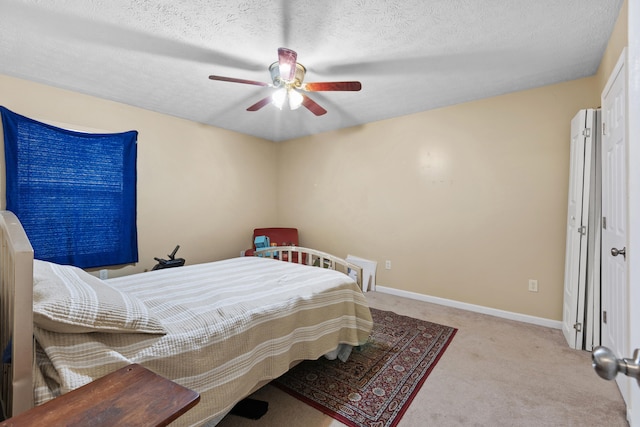 bedroom with a textured ceiling, light colored carpet, and ceiling fan