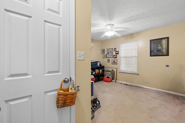 carpeted office space featuring ceiling fan and a textured ceiling