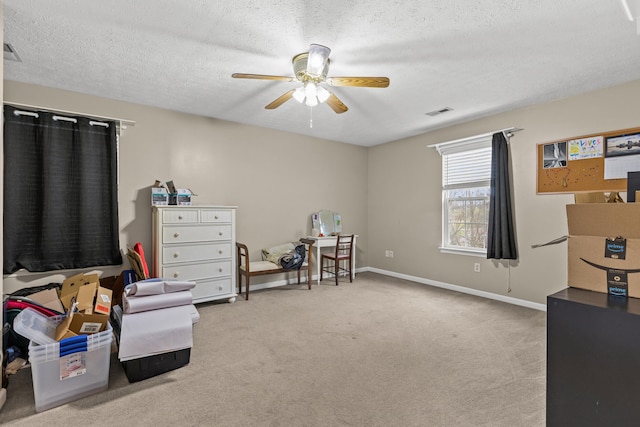 sitting room featuring ceiling fan, light colored carpet, and a textured ceiling