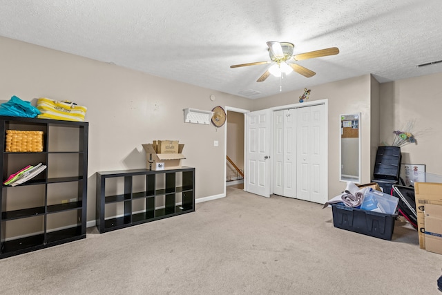 miscellaneous room with ceiling fan, light colored carpet, and a textured ceiling