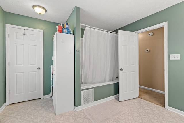 interior space with shower / bathtub combination with curtain and a textured ceiling