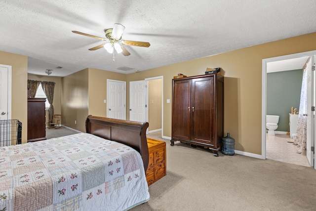 carpeted bedroom featuring ceiling fan, a textured ceiling, and ensuite bath