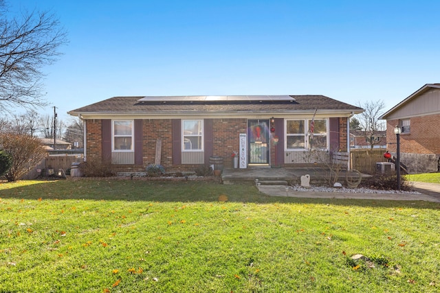 ranch-style home featuring solar panels, central air condition unit, and a front yard