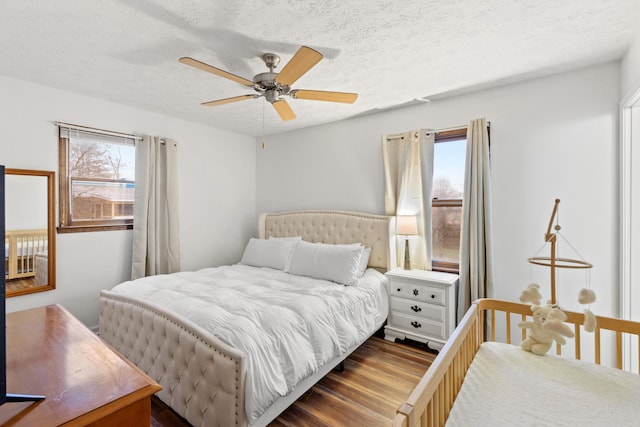 bedroom with hardwood / wood-style floors, ceiling fan, and a textured ceiling