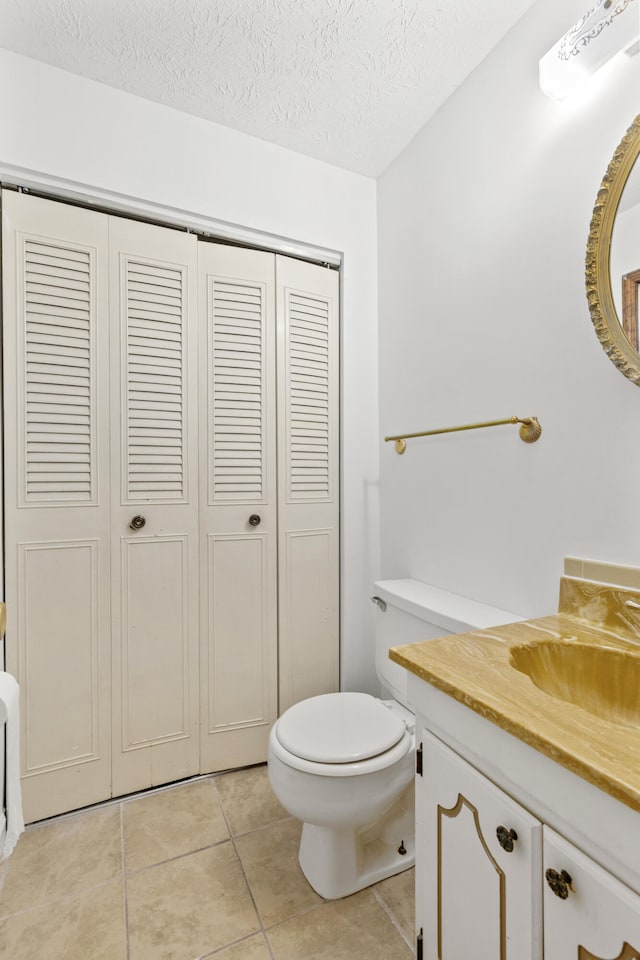 bathroom featuring tile patterned floors, vanity, toilet, and a textured ceiling