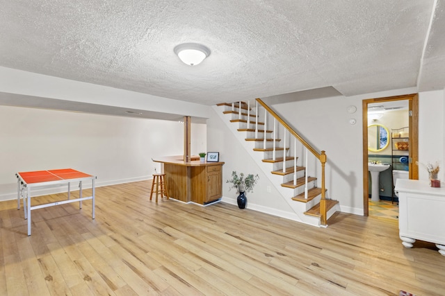 interior space with sink, light wood-type flooring, and a textured ceiling