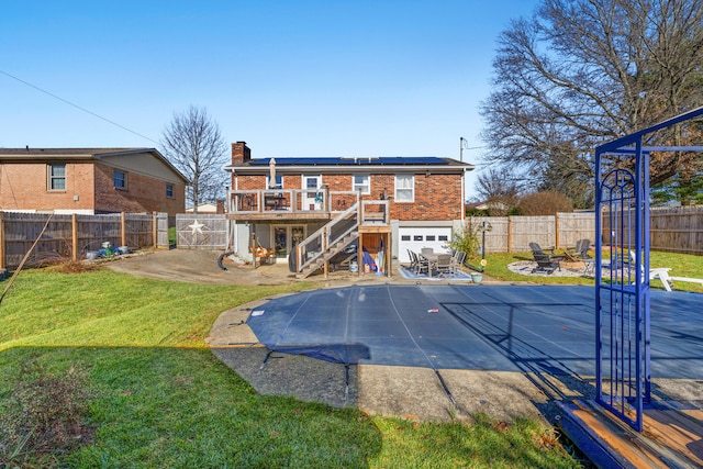 back of property with solar panels, a patio, a swimming pool side deck, and a lawn