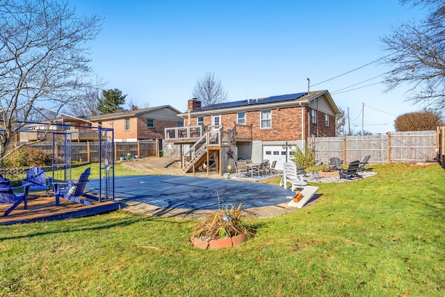 rear view of house featuring a pool side deck, solar panels, a yard, and an outdoor fire pit