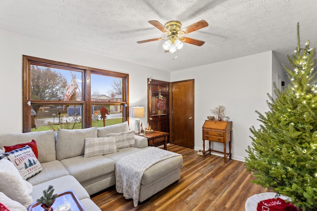 living room with a textured ceiling, ceiling fan, and dark wood-type flooring