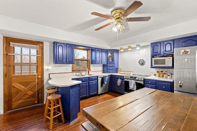 kitchen featuring sink, dark wood-type flooring, blue cabinets, a kitchen bar, and appliances with stainless steel finishes