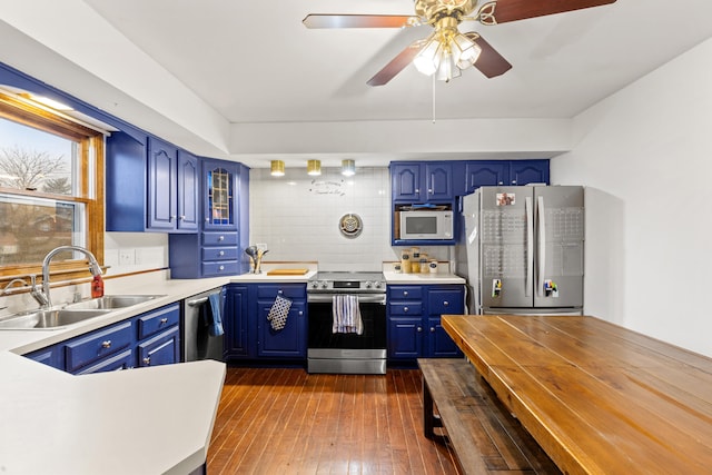 kitchen featuring blue cabinetry, sink, stainless steel appliances, and dark wood-type flooring