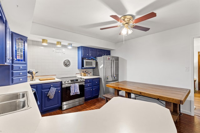 kitchen featuring stainless steel appliances, ceiling fan, sink, blue cabinetry, and dark hardwood / wood-style floors