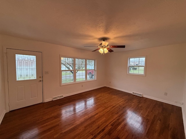 foyer entrance featuring a textured ceiling, ceiling fan, dark wood-type flooring, and a wealth of natural light