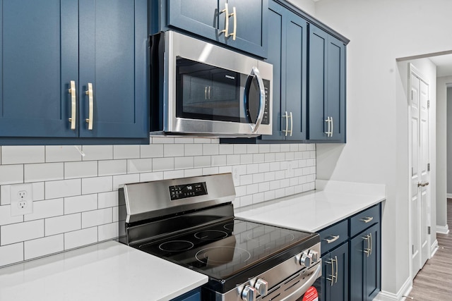 kitchen featuring decorative backsplash, hardwood / wood-style floors, stainless steel appliances, and blue cabinets