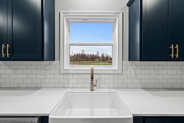 kitchen featuring blue cabinetry, decorative backsplash, dishwasher, and sink